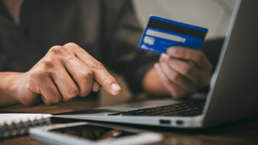 Man using lap top with credit card in hand