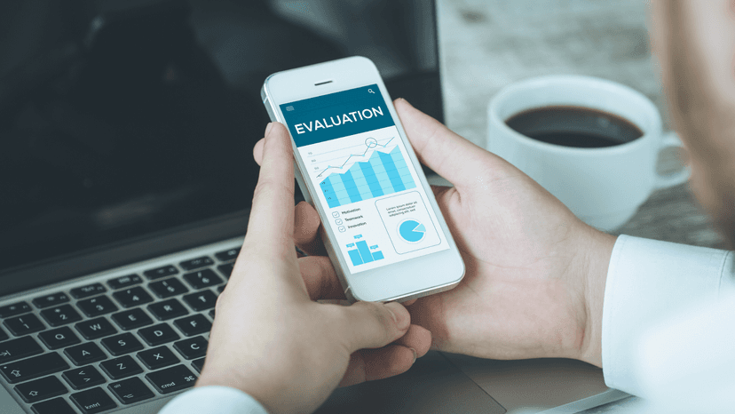 Man holding mobile phone displaying charts and graph