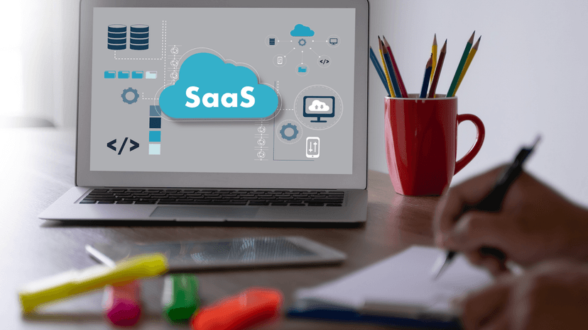 person working a desk with laptop, laptop displays SaaS