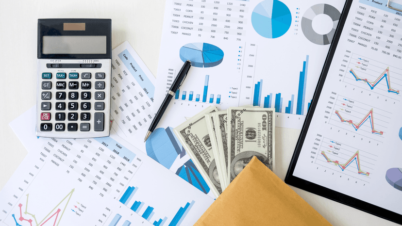 calculator, cash, and various reports with charts and graphs sitting on table