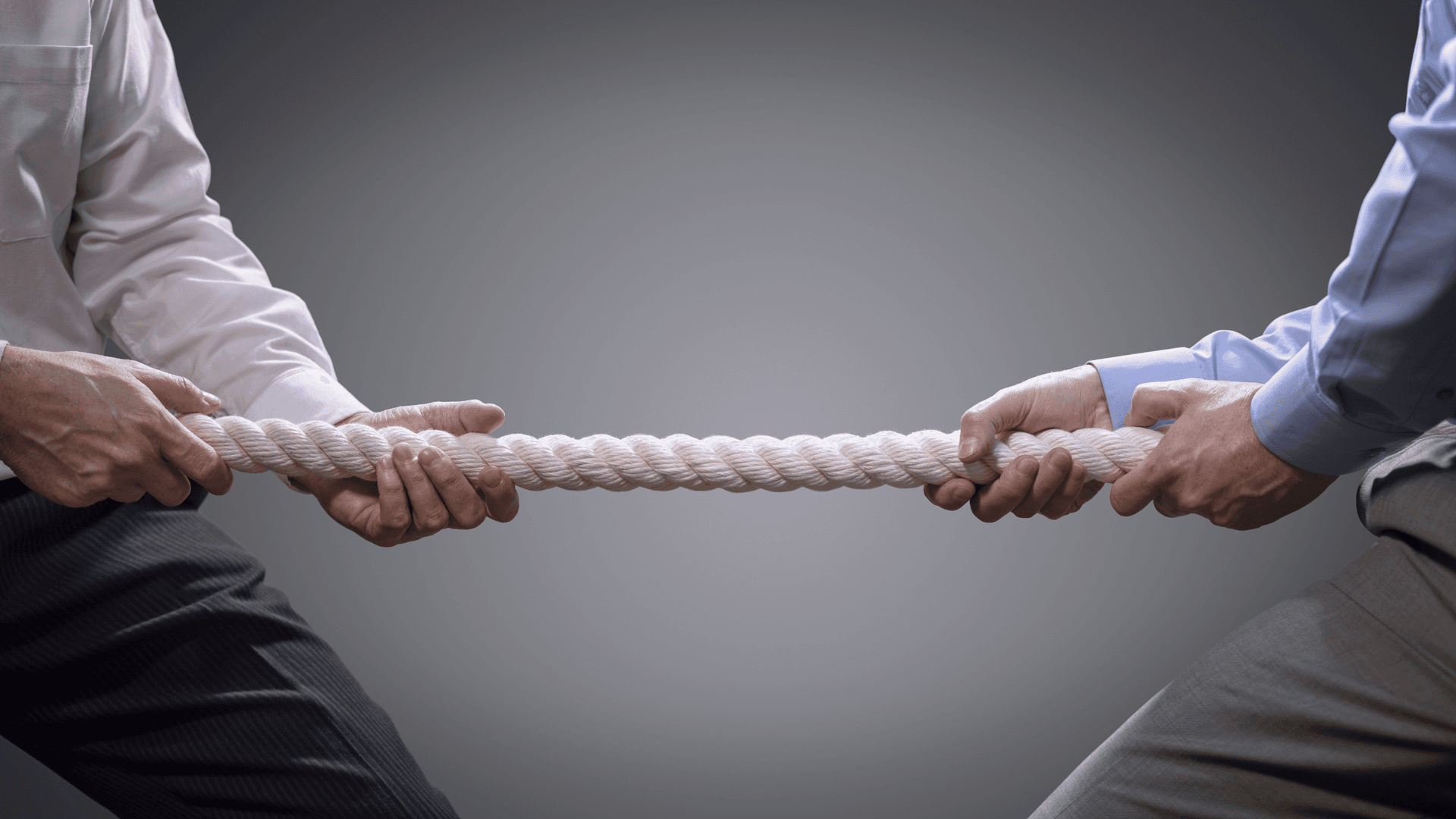 two sets of arms in business professional dress tugging on rope